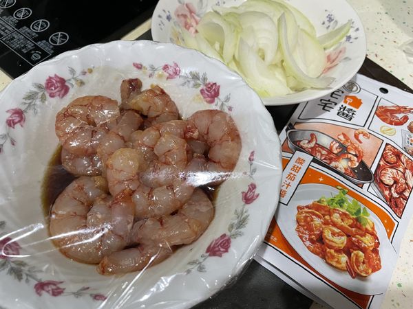 將蝦子放入醃料中醃至30分鐘；洋蔥切絲，準備茄汁醬