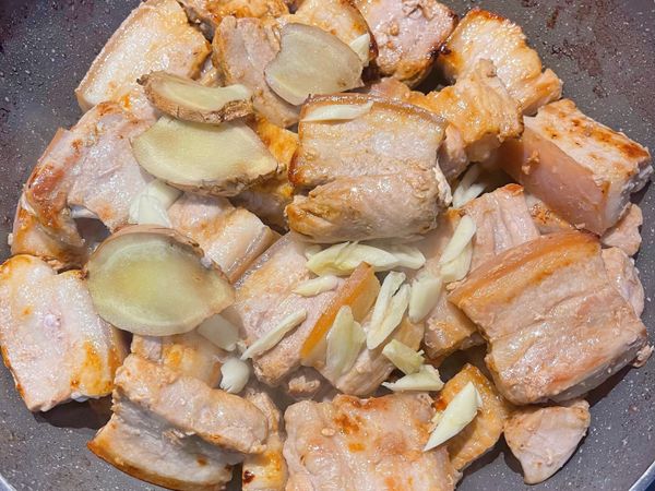 全部五花肉都煎好後，放入蒜頭、薑片炒香；
