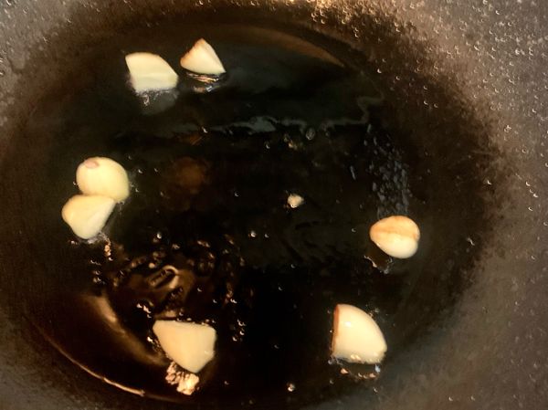 熱油後，轉小火放入蒜頭爆香至蒜頭成微焦狀，再放入已醃製好的雞胸肉；翻炒均勻後蓋鍋蓋小火悶5分鐘，再開蓋翻炒至雞胸肉表面也呈現微焦狀