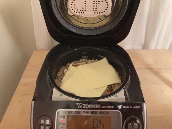 打開上蓋，放入起司片，鋪在飯上面，蓋上鍋蓋，燜3-4分鐘