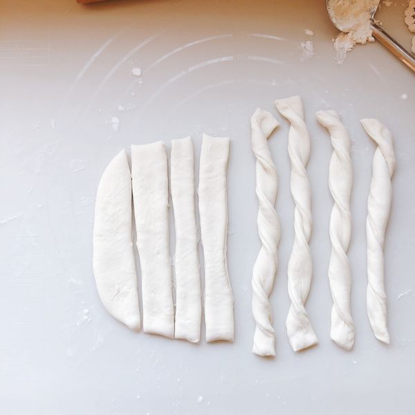 左右兩手往反方向扭轉成麻花狀，然後將麵包棒放在烤盤上。