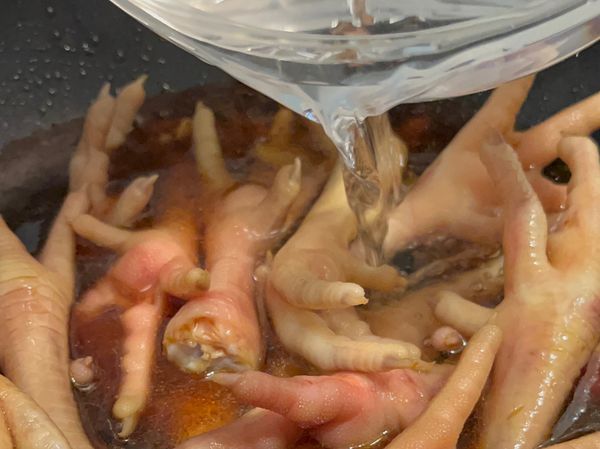 3、加入醬油、米酒、砂糖炒香後拌入雞爪，再加水淹過食材
