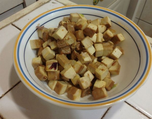 倒入一大匙油，小火爆香紅蔥頭與蔥白，待飄出香味以後放入豆乾翻炒約三分鐘至表皮呈金黃色即撈起豆干備用