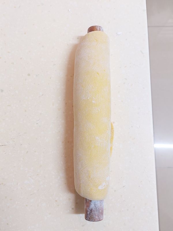 用擀杖將麵片捲起，繼續擀開（把中間擀薄）