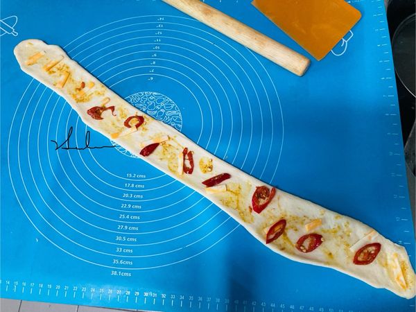 最後一個小麵糰，一樣桿成長條狀，先放入辣椒，再放上切好小條的起司條，都需要有間距，最後再將咖哩醬用小湯匙的背面塗在麵糰上，盤子上的殘留醬也需用手指將盤子內的咖哩醬塗在麵糰上。(不是節省，而是咖哩醬在麵糰內的量本來就是需要少少的分佈)咖哩辣椒起司口味。