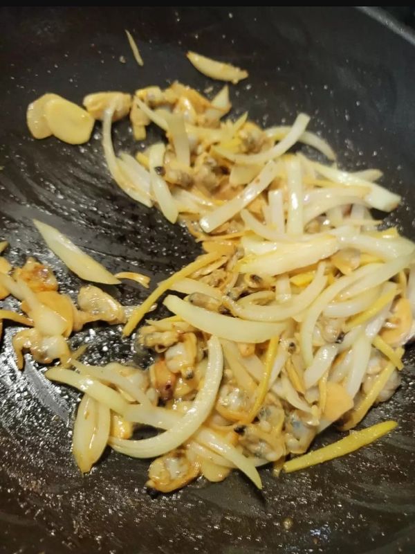 薑和洋蔥切絲,蒜切片,油先爆薑蒜,加蛤蜊肉及調味料（沙茶醬1匙 醬油 1匙 糖半匙 水2匙調勻）炒至蛤蜊上色入味，再加切絲的洋蔥炒，最後起鍋前再加2匙米酒炒勻