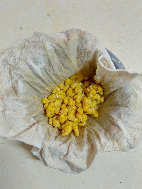 玉米粒用開水洗2遍（可以不洗），加入紗布中擠乾