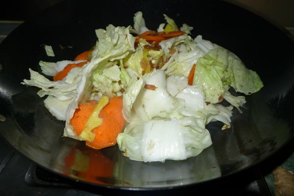 放入乾蝦仁與薑片爆出香味後加入紅蘿蔔拌炒，再將大白菜加入同拌炒，待白菜已軟化加一點水以中小火燜煮。