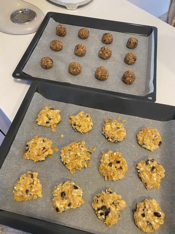 把剩下的玉米片放在一個盤子裡輕輕壓碎，將麵團揉成一個個圓球狀，沾上壓碎的玉米片並輕輕裹上一層，稍微壓平麵團，排列在烤盤上一樣要保持一些空隙哦。