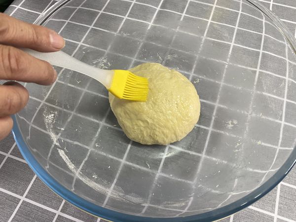 加入適量橄欖油在麵上,塗抹均勻,蓋上保鮮膜,進行第一次發酵約60分鐘