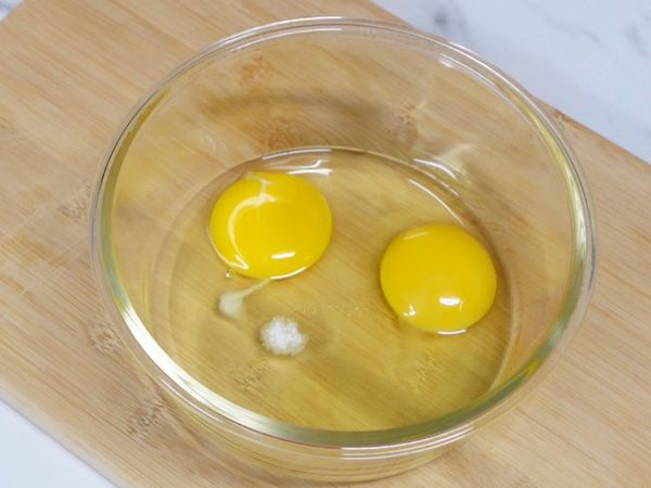 打入兩顆雞蛋到碗中，加入少許鹽巴，再將其打散