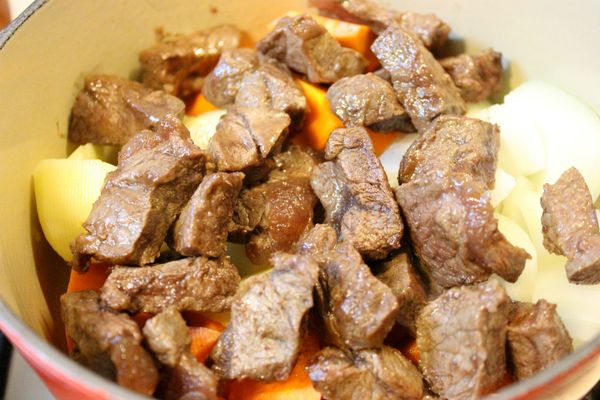 取鑄鐵鍋或厚底部的鍋子，先放入蔬菜丁，上面放上煎好的牛肉塊。