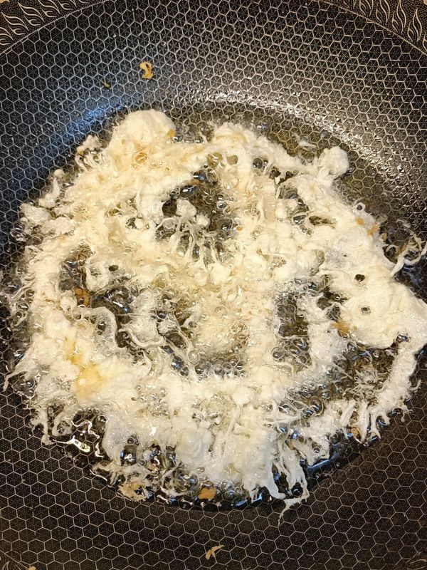 先準備一個炸物用的濾網備著，開中小火燒鍋熱油，油差不多炸物一般會用的量，油多比較好炸，油熱了就可以拿調好的粉漿倒入濾網過篩下油鍋（粉漿分三次炸），手拿高濾網可隨意畫圈畫三下，讓粉漿不要煎成大塊狀就好