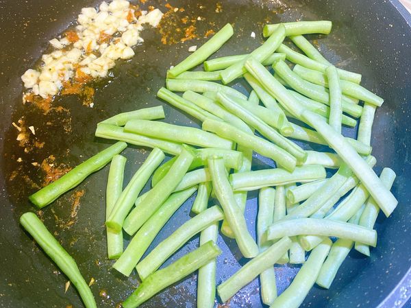 用雞油炒香蒜末，再加入四季豆拌炒。