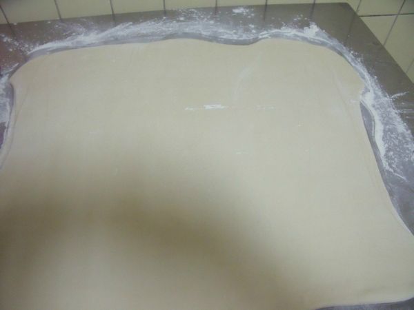 再擀成長方形,刷掉麵皮上的粉,抹少許的水。