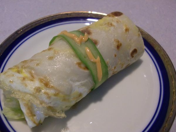 把蛋餅切成長條形，如變奏曲（1）的做法擺上美生菜和培根等，然後捲成圓筒狀，切成兩段，在中間用小黃瓜片包捲固定，淋上一些千島沙拉裝飾。