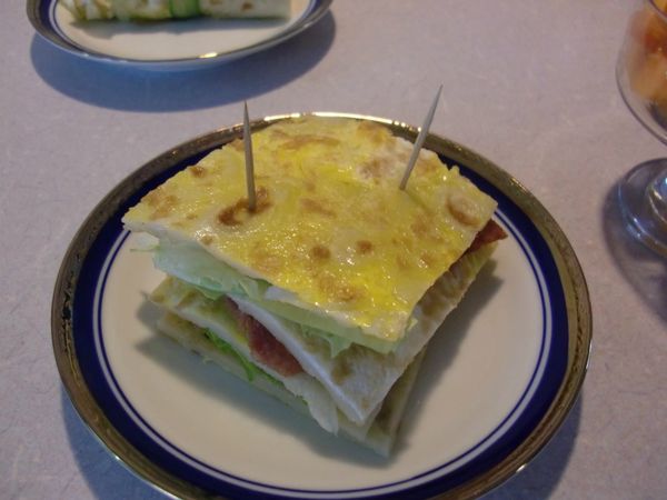 把蛋餅修邊切成四個正方形，再把抹上沙拉的生菜和培根一層蓋上一片蛋餅，重複三次動作，最後蓋上一片蛋餅，用牙籤兩對角固定即完成。