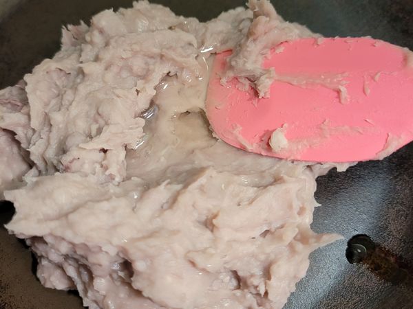 將拌好澱粉糖水的芋頭餡放入平底鍋中，加入植物油，全程用小火拌炒成團。