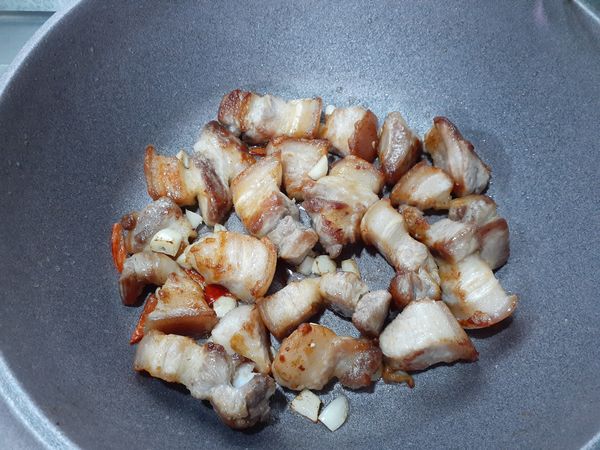 將煎好的肉取出，在鍋裡留適量的豬油，多的盛起來可以用在其他地方。
將蒜頭、辣椒用油爆香，再把肉放回去拌炒一下。