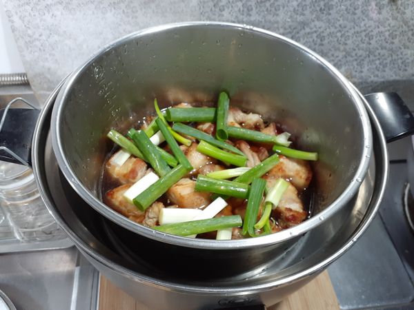 將肉、醬油、米酒、味醂、水、蔥段放入電鍋內鍋，外鍋放一杯水。蓋上鍋蓋燉煮。