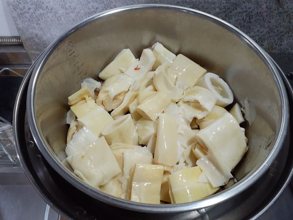 用剛才炒過肉、蒜頭的鍋子，不要再另外加油，把桂竹筍也稍微拌炒過，沾上蒜頭辣椒和肉的香氣。
等電鍋開關跳起，把炒過的桂竹筍放入，再在外鍋放一杯水，蓋上鍋蓋燉煮。