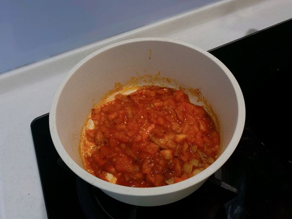 爆香後，接著加入蕃茄丁及番茄醬，繼續翻炒。