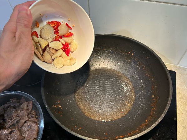 牛舌片全部燙熟後，將舊油倒掉換新油，開大火加入料頭（蔥薑蒜辣椒）爆香