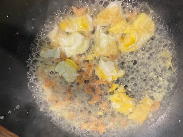 加入蝦米水、蒜頭中火拌炒