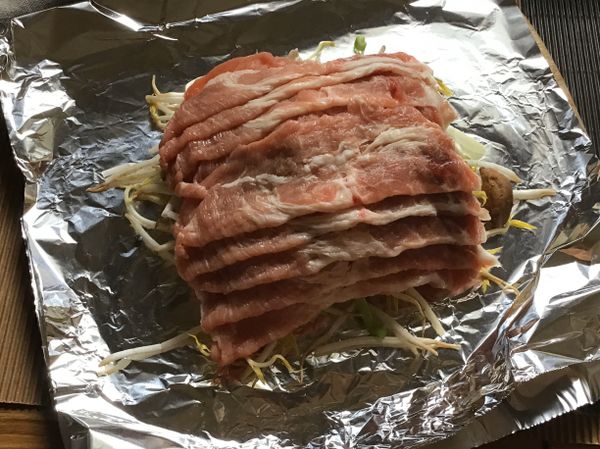 ❷蓋鋪上肉片，淋上米酒、烤肉醬，再撒點蔥蒜辣椒