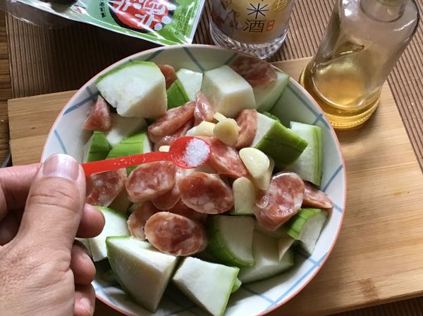 ❸絲瓜舖盤中，再放上香腸片、蒜片
❹撒點鹽巴、淋點米酒、香油，電鍋蒸煮，外鍋1杯水蒸熟