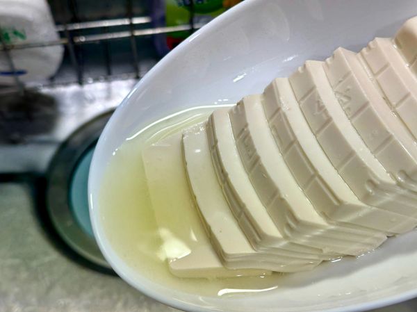 將步驟(2)的嫩豆腐從電鍋中拿出，倒掉盤底的水。