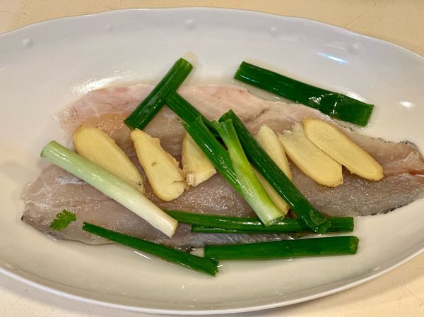把薑片及青蔥放在魚片上加入少許的米酒及水