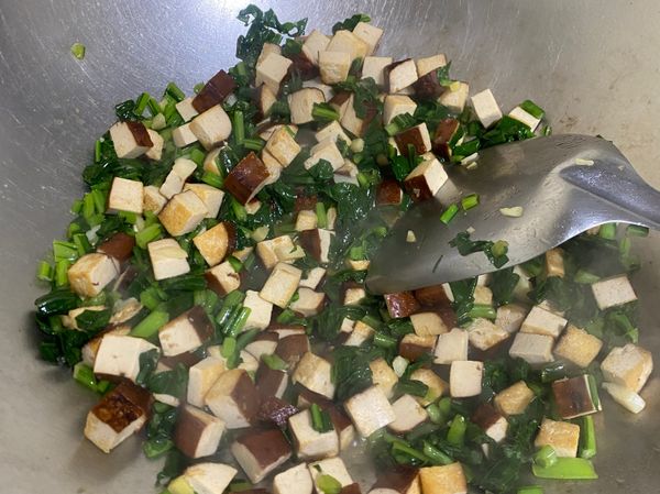 已上色的豆干加入雪菜拌炒到有香味，再倒入調味醬料，充分嗆香並使味道融合。最後灑一些胡椒粉即可起鍋。