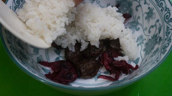 取一大碗公抹上少許油，底排上Ｑ梅、洛神花蜜餞。
鋪上一層卑南米白飯。