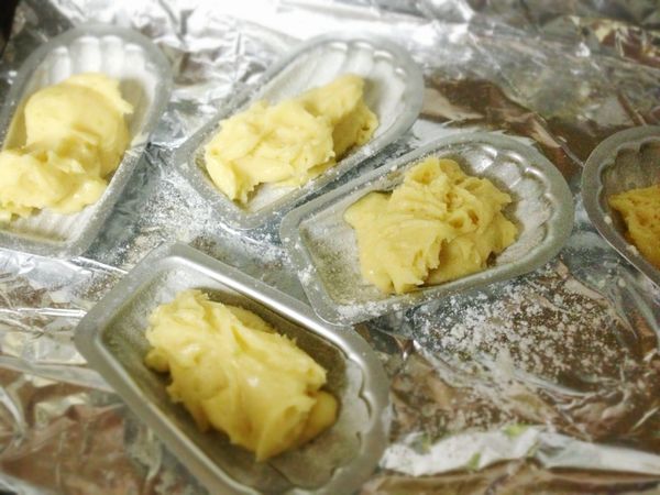 將瑪德蓮模型和麵糊從冰箱取出，挖取可填滿3/4模型的麵糊放入模型中央，注意！不要抹平麵糊，將瑪德蓮放入烤箱中，烤約8~9分鐘。烤完後從模型中取出瑪德蓮並在架上放涼。