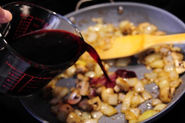 接續將紅酒倒入炒鍋內以中大火翻炒，翻炒過程中也將沾附在鍋壁的油脂香氣融入湯汁中，直到目視紅酒略為收乾約20%，即可將整鍋內容物倒進先前燉鍋裡。