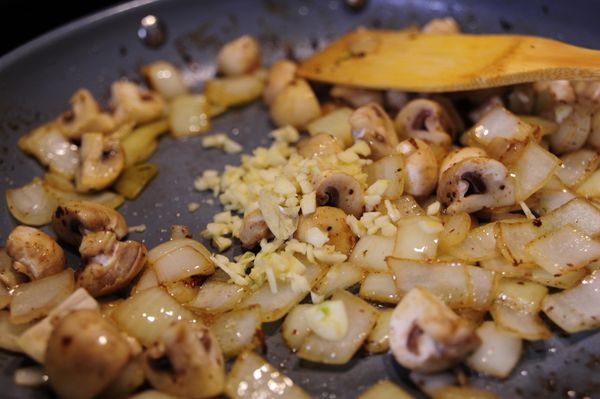 同一個炒鍋放入洋蔥丁以中火翻炒，如此時炒鍋內油量不足可補充少量橄欖油，洋蔥大約翻炒5分鐘後加入洋菇炒軟，再加入大蒜末翻炒約1~2分鐘即可。
