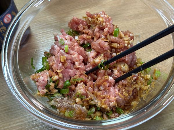 利用筷子攪拌材料，讓肉吸收調味料並產生黏性，加入香油攪拌均勻