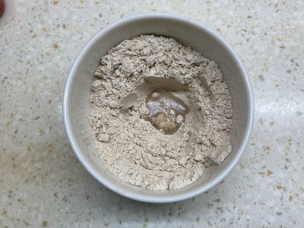 粉類中間挖一個洞，倒入溶有糖和酵母粉的清水。