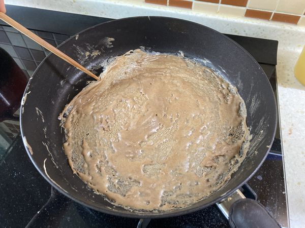 待表面凝固後，用筷子輔助在邊緣撩出一個縫縫，再用萬能雙手把餅整張捏起來翻面。