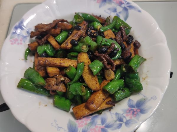 鍋內留空間，加入豆豉略炒至產生香氣；再加入糯米椒拌炒1分鐘，以醬油/少許鹽調味。最後加回肉絲，再續炒1分鐘即可完成。