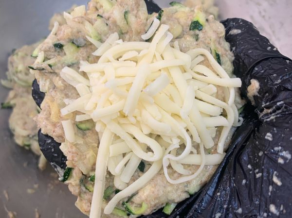 櫛瓜餅攤開，加入乳酪絲，包起來。