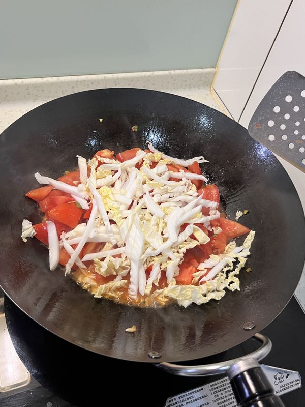 再丟入切好的白菜絲，繼續煸炒，炒至白菜斷生軟爛狀