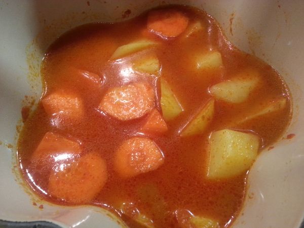 燒熱另一鍋，下已炸過的馬鈴薯，紅蘿蔔，紅咖喱醬和水中火煮至大滾。