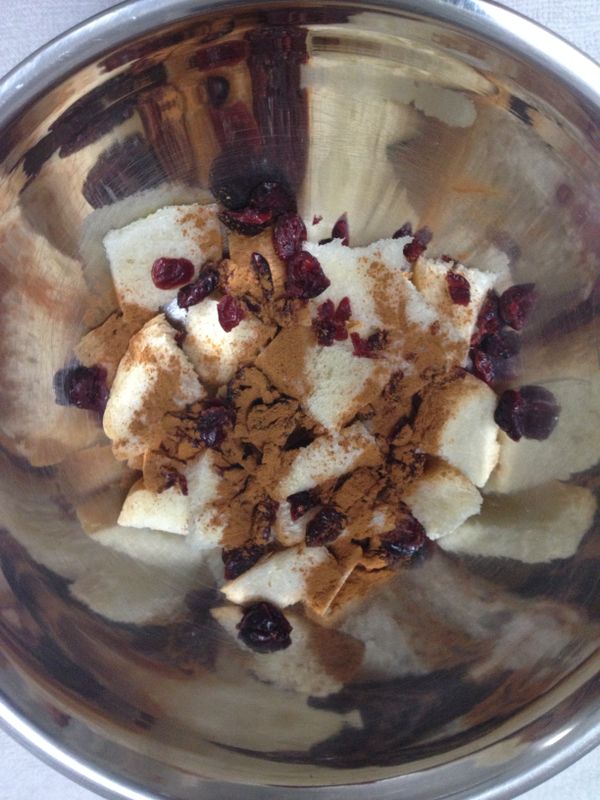 將麵包粒放入盆中，加入玉桂粉及紅莓乾／提子乾攪混。