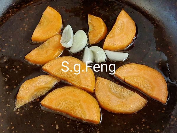 3.起鍋開小火，放入1大匙的食用油，放入蒜頭與紅蘿蔔，炒出香氣。