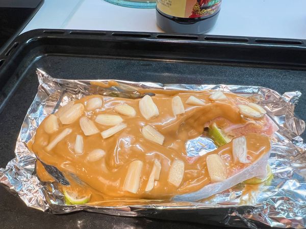 盤底放檸檬片，魚抹滿美乃滋，上面放蒜片。