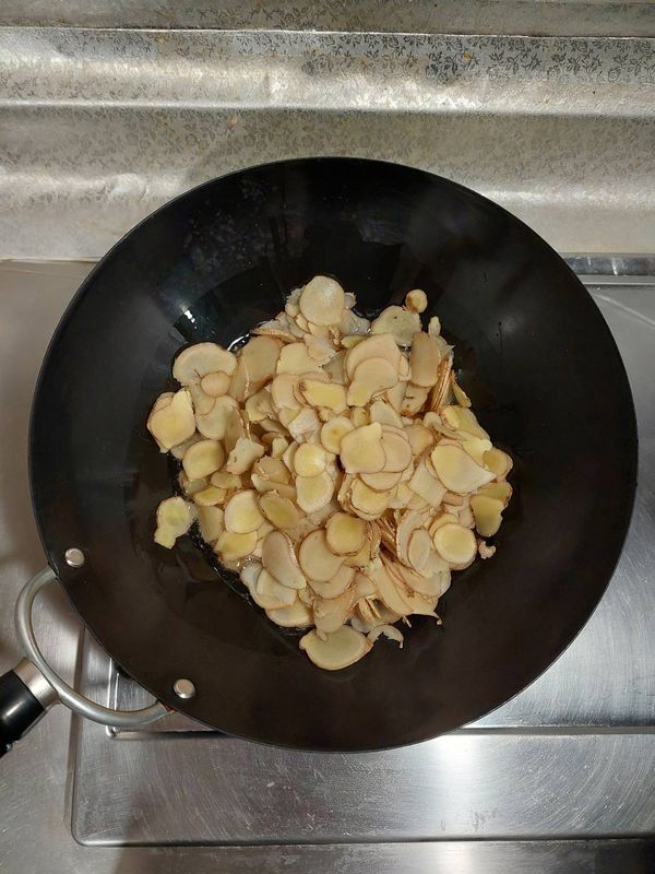 鐵鍋燒熱，倒入葵花油潤鍋，再下薑片