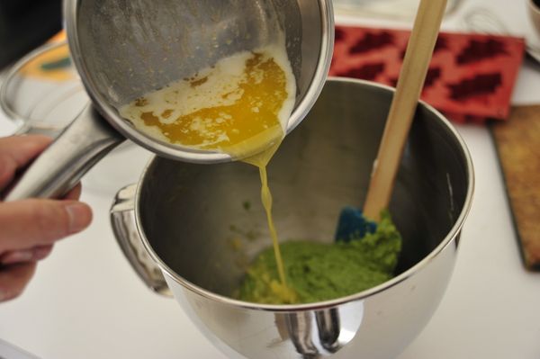 將稍放涼的融化奶油分成兩次，緩慢加進麵糊中，一邊倒入一邊混拌均勻至完全融合。