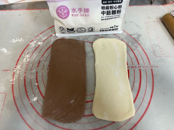 取一個100g巧克力麵團，折三折後再桿成長條型約20X10cm，另一個白色麵團也是折三折後再桿成長條型約20X10cm